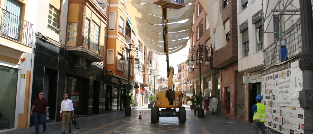 Operarios colocando, este jueves, los toldos en el primer tramo de la calle Corredera.