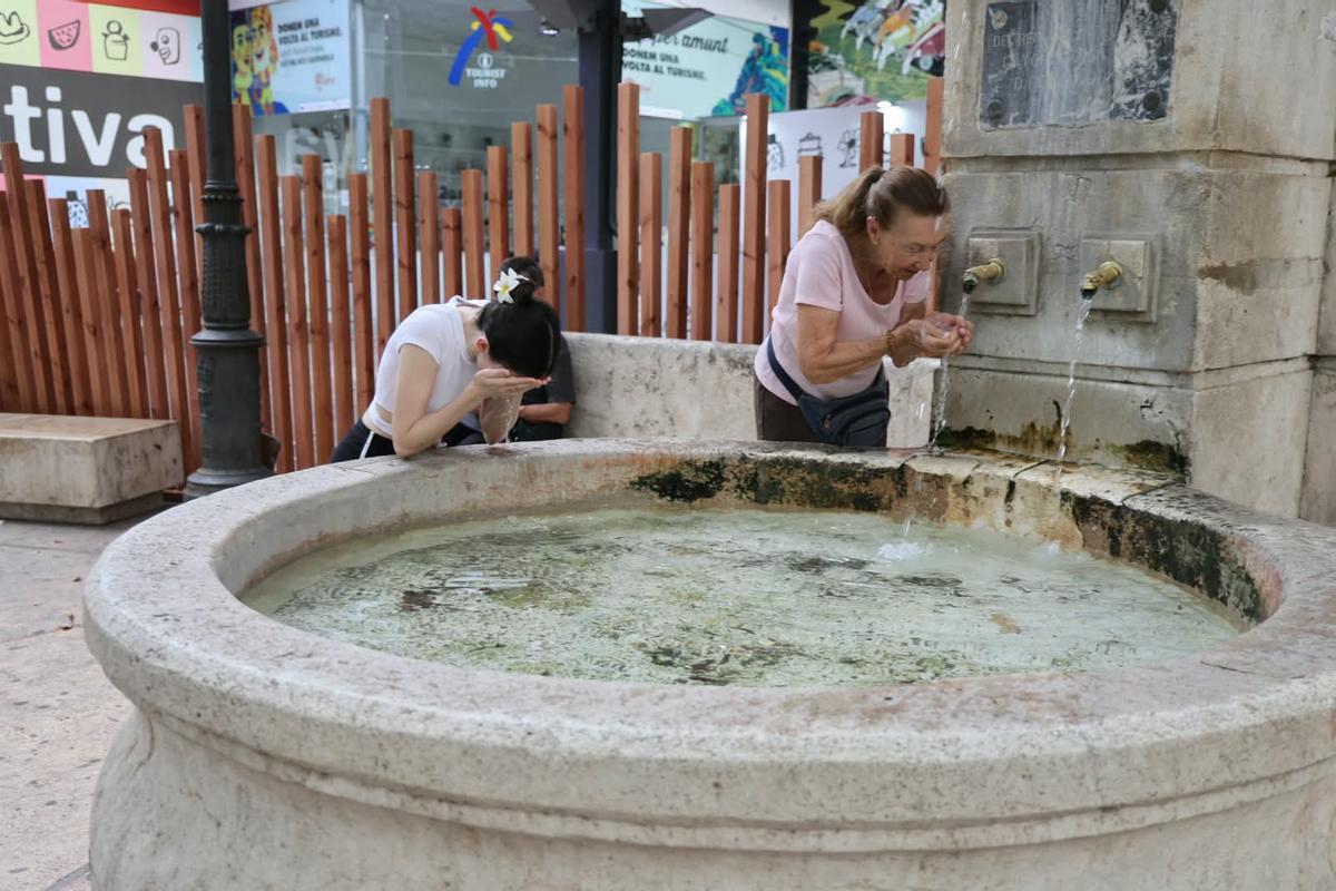 Dos mujeres se refrescan en la Font del Lleó.