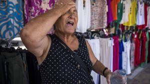 Una trabajadora del mercadillo de Toledo se protege contra el calor, durante el verano de 2023.