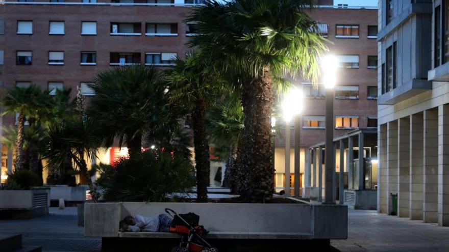Una mujer duerme en un banco de la plaza Mariano Aguerri de Zaragoza. | ÁNGEL DE CASTRO