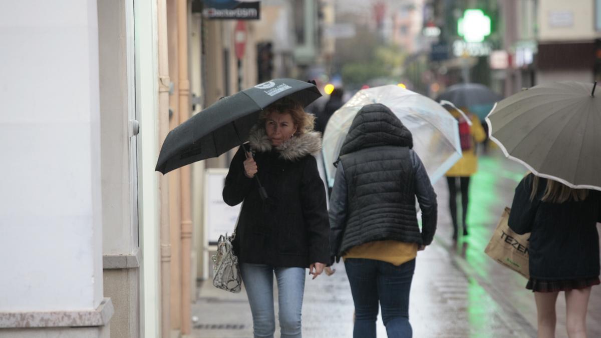 Una mujer se protege de la lluvia en un día ventoso en Castellón.