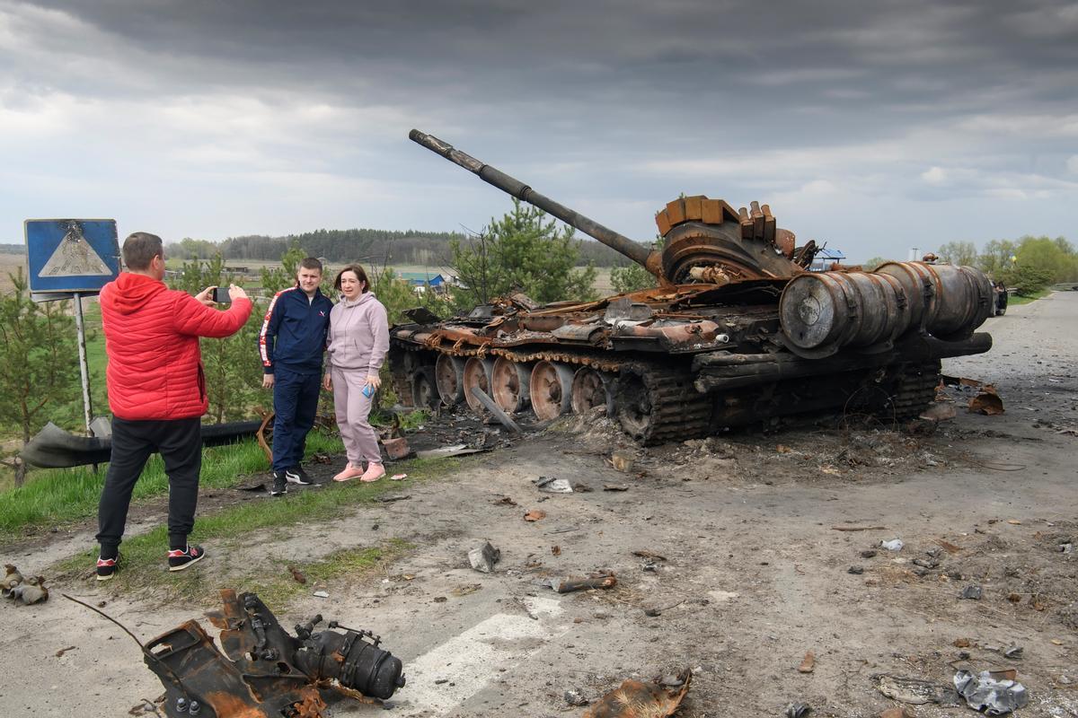 La gente fotografiándose con los escombros de la maquinaria militar rusa destruida, en el pueblo de Rusaniv.