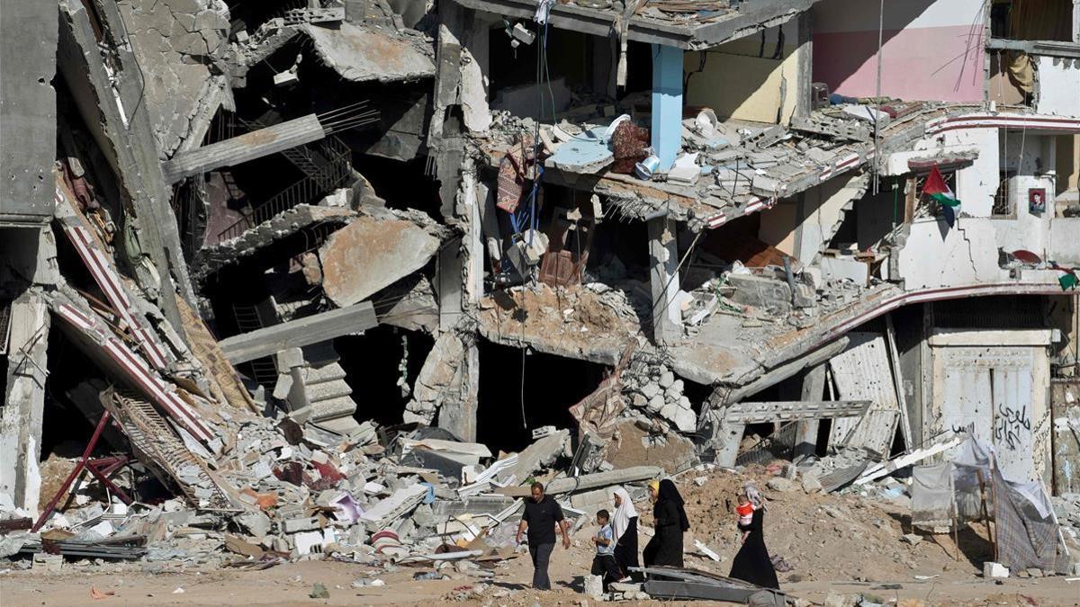 Una familia atraviesa una calle con edificios destrozados en Gaza, en el marco del enfrentamiento entre Hamás e Israel en 2014.
