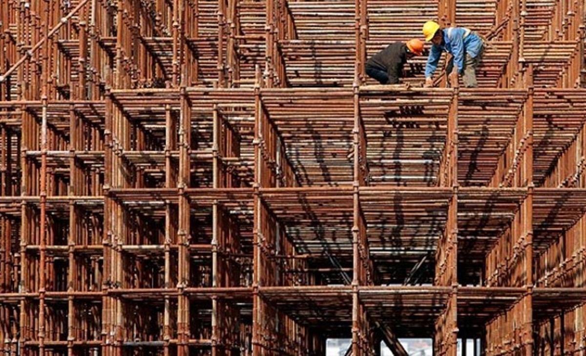 Unos trabajadores construyen la estación de tren de Nanjing Sur (China) sobre unos andamios de bambú.