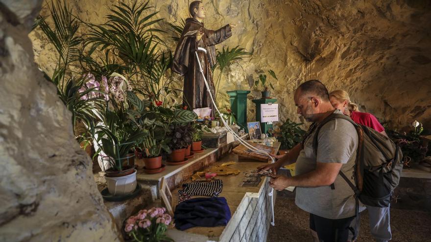Dos peregrinos cumpliendo con la tradición de tocar el cordón de la imagen de San Pascual.