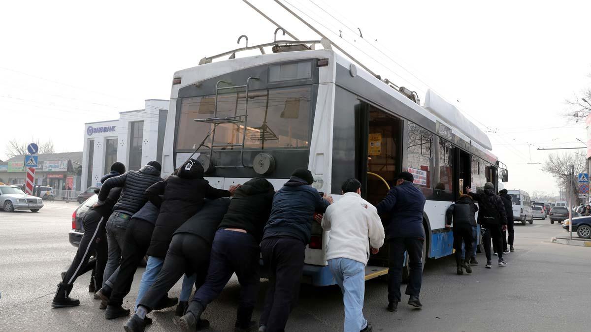 Varias personas intentan mover un autobús eléctrico para por el apagón en Bishkek, Kirguistán.