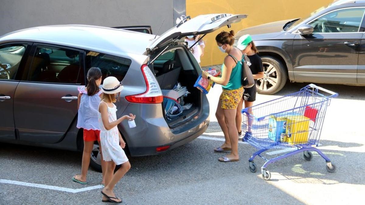 Una familia francesa coloca bolsas en su coche, tras comprar en un supermercado de La Jonquera