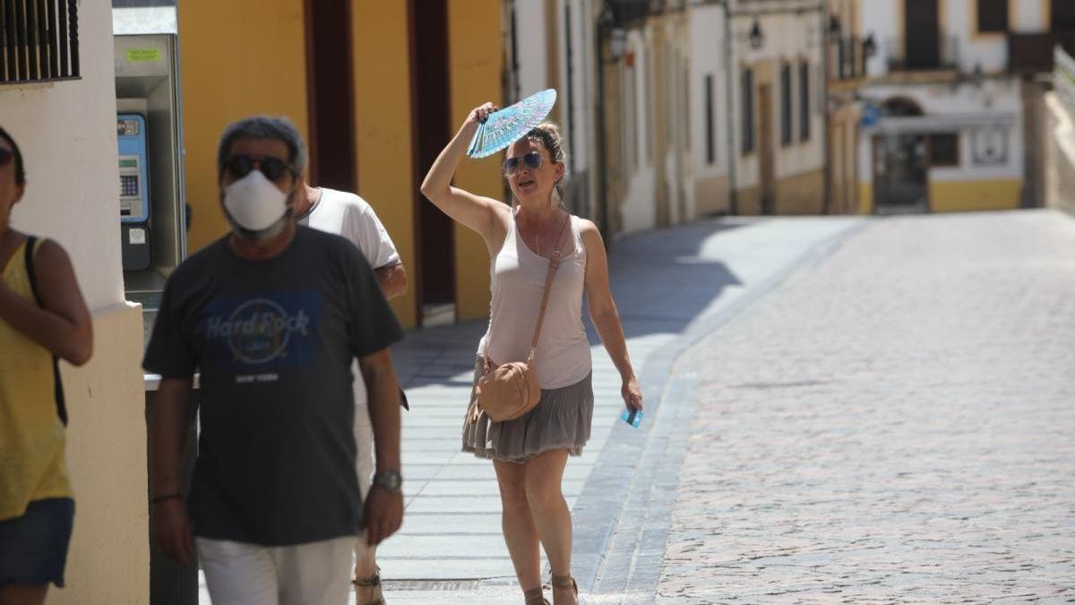 Una mujer se cubre la cabeza con un abanico durante un día de calor en Córdoba.