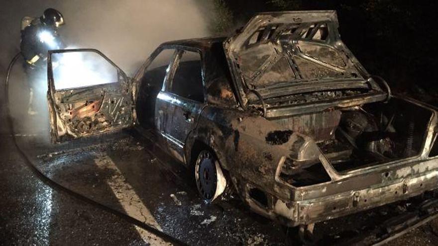 Los bomberos apagan el fuego en el coche incendiado