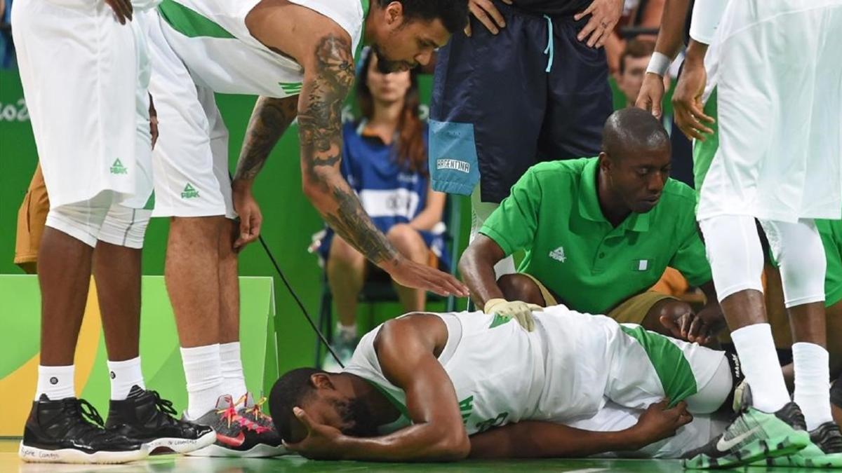 Shane Lawal se duele en el suelo tras sufrir la lesión mientras es atendido por los médicos nigerianos.