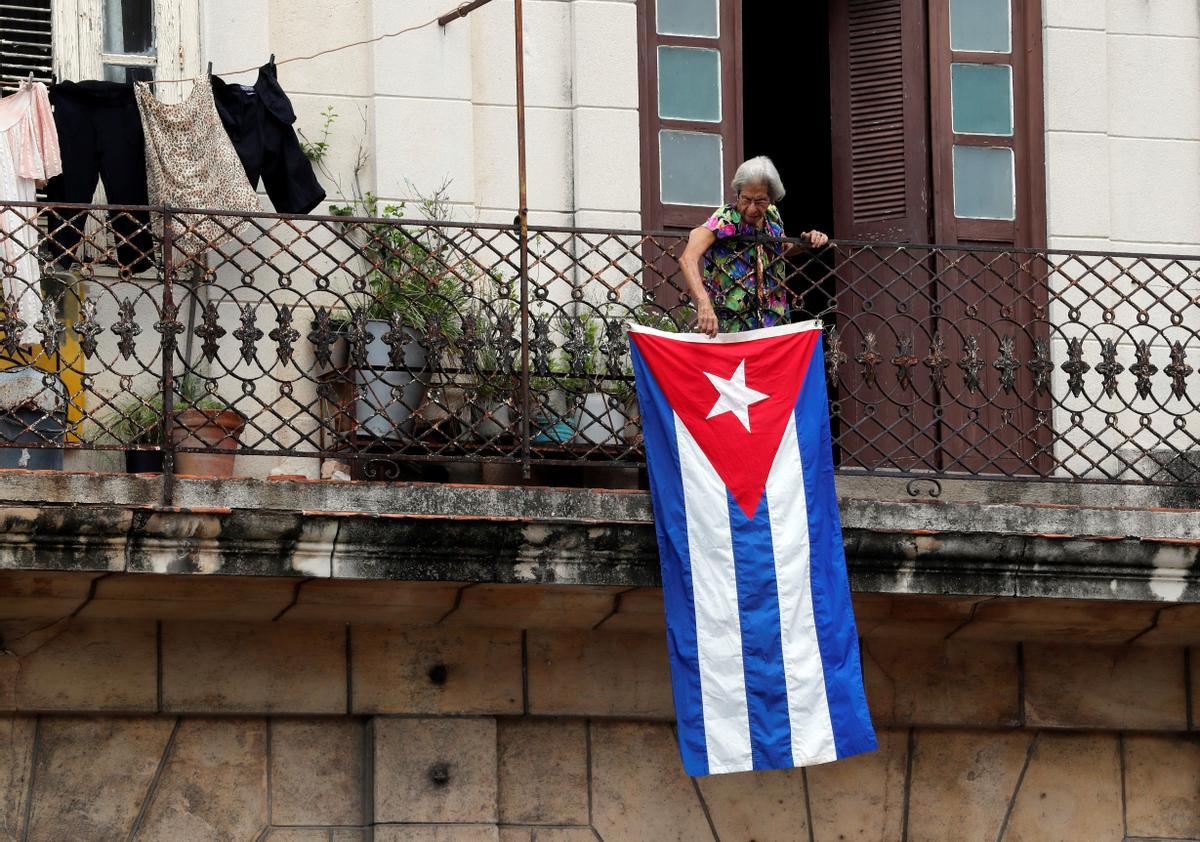 Una mujer sale al balcón donde se expone una bandera cubana, en La Habana, Cuba.