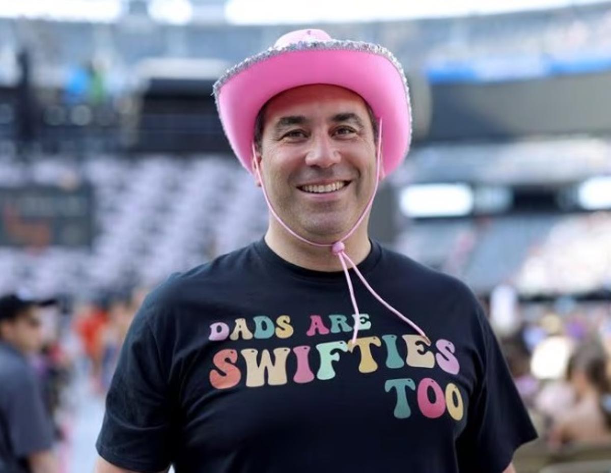 Un hombre con una camiseta donde reza 'Los padres también somos swifties'.