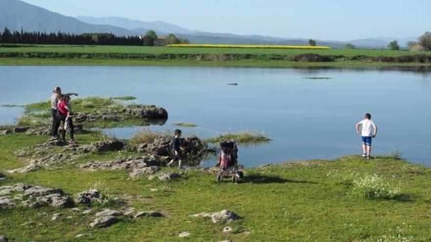 Diverses persones observaven l&#039;aigua que ha omplert el clot d&#039;Espolla, aquesta setmana.