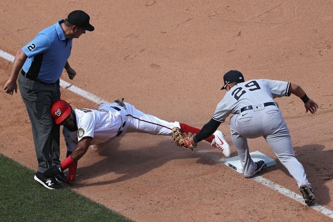 Emilio Bonifacio # 27 de los Nacionales de Washington es sorprendido robando la tercera base por Gio Urshela # 29 de los Yankees de Nueva York durante la novena entrada en el Parque Nacional.