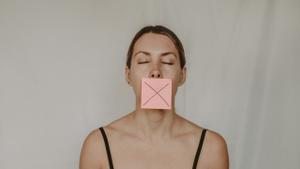 Una mujer con la boca tapada con un trozo de papel.