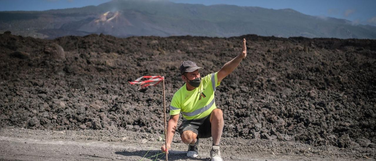 Un operario marcando el trazado de una carretera afectada por las coladas de lava procedentes de la erupción volcánica de La Palma.