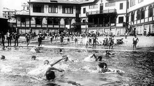 La Escola del Mar, al fondo, obra de Josep Goday, y varios de sus alumnos, en primer plano, en la hora del baño.