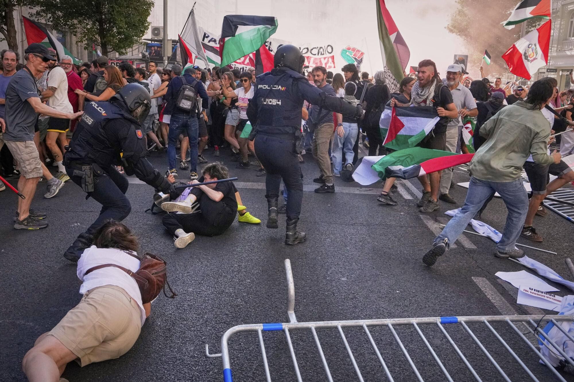 Police try to disperse protesters who block the road in an attempt to disrupt the twenty-first stage of the Spanish cycling race La Vuelta, from Alalpardo to Madrid, Spain, Sunday, Sept. 14, 2025. (AP Photo/Manu Fernández)