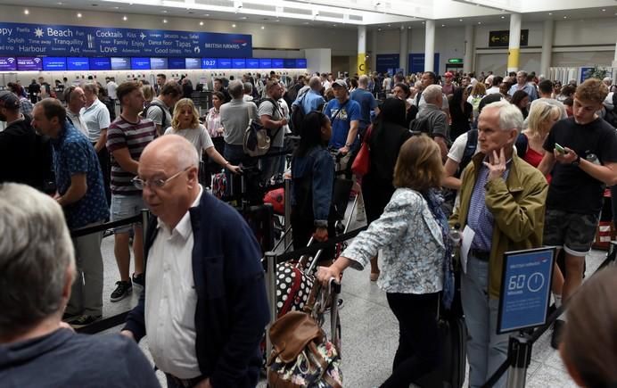 People queue with their luggage for the British ...