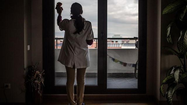 Una empleada doméstica limpia el cristal de una vivienda. | // LOC