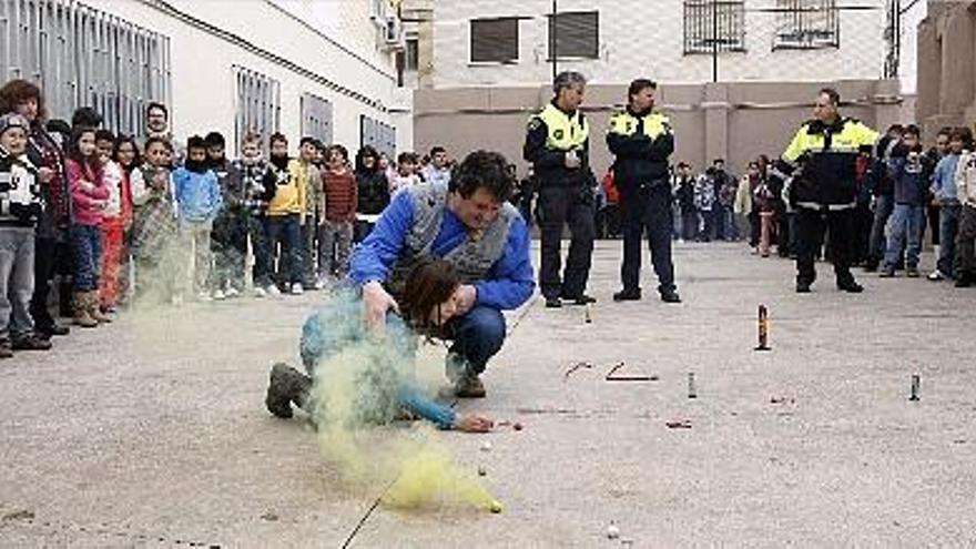 Un pirotécnico explica a una alumna del colegio San Roque cómo se debe encender un petardo en el suelo.