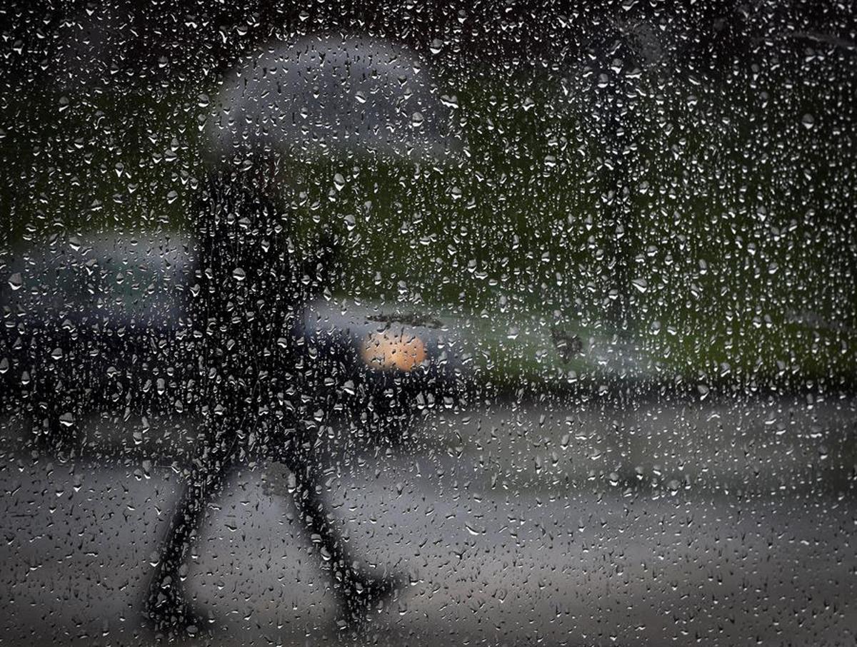 Un hombre camina bajo la lluvia.