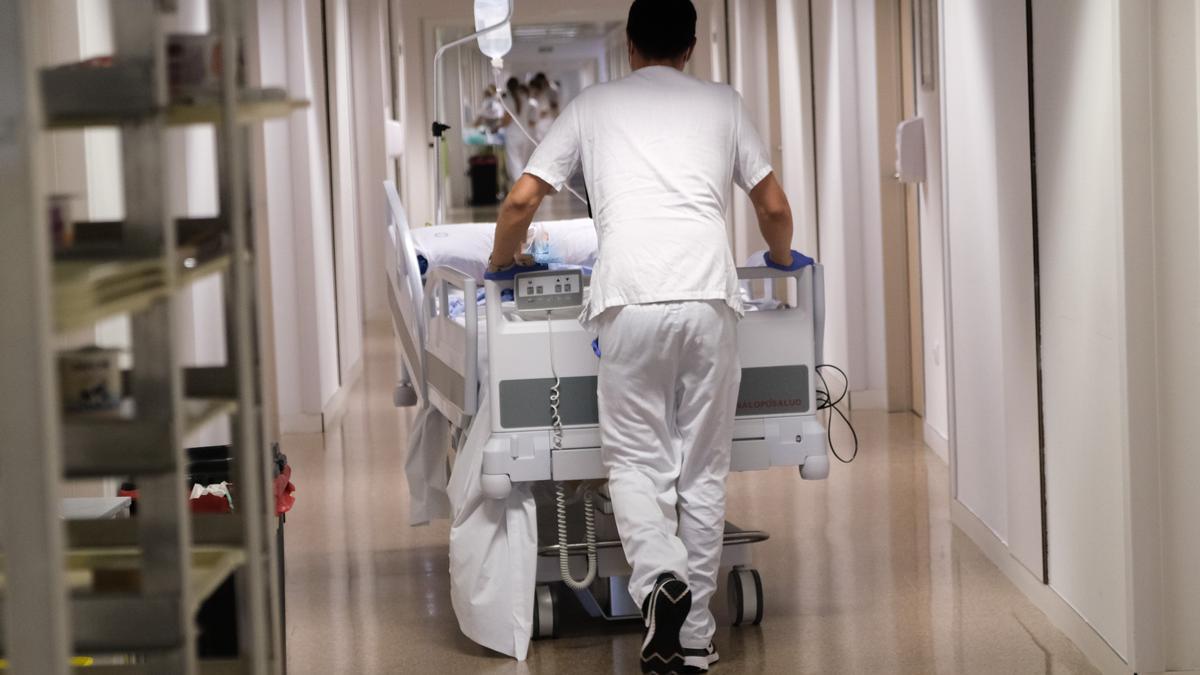 Un celador trasladando a un paciente en un hospital público.