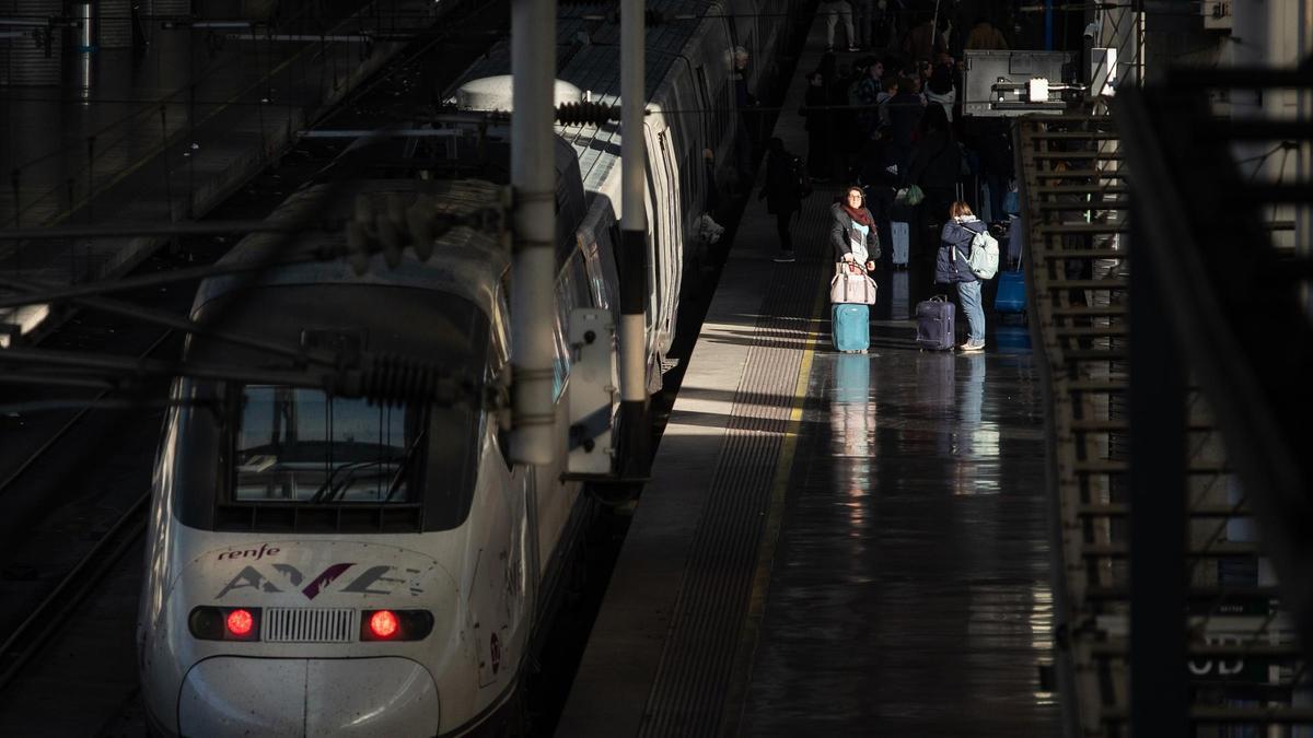 Pasajeros junto a un AVE estacionado en la estación de Atocha-Almudena Grandes.