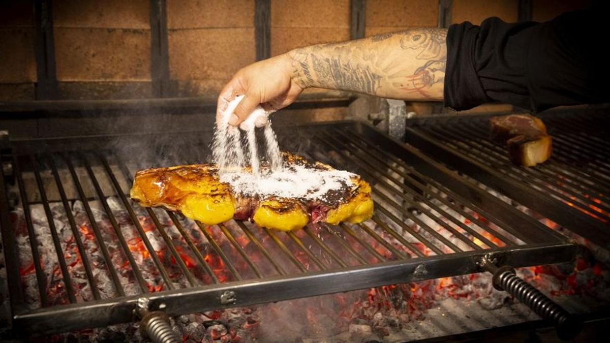 Chuletón con sal sobre una parrilla inclinada y con varillas.