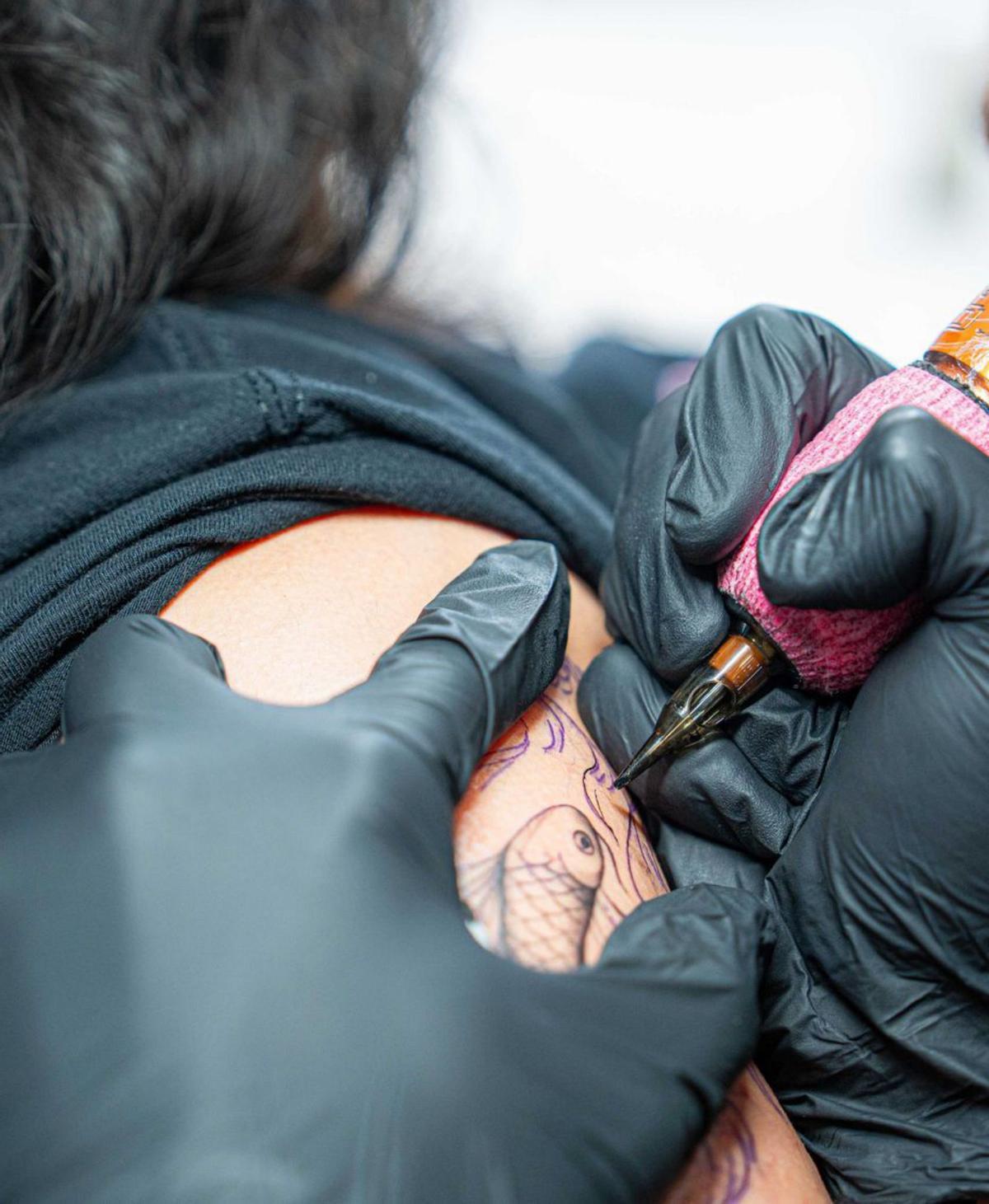 Un tatuador, trabajando sobre la piel de un cliente.