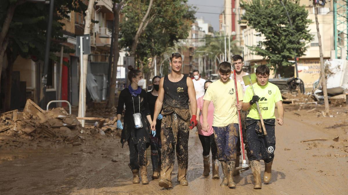 Jóvenes voluntarios caminan por las calles embarradas de Albal.