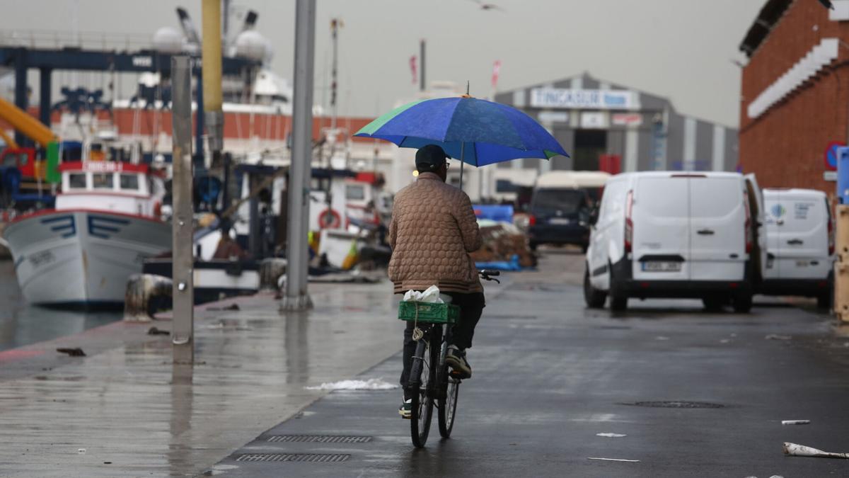 Persona paseando con su bicicleta bajo la lluvia en Barcelona.