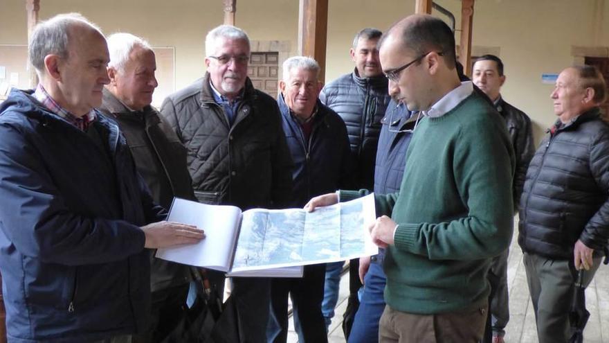 Antonio Fernández y el alcalde, José Víctor Rodríguez, despliegan el mapa del proyecto en presencia de vecinos de Llano.