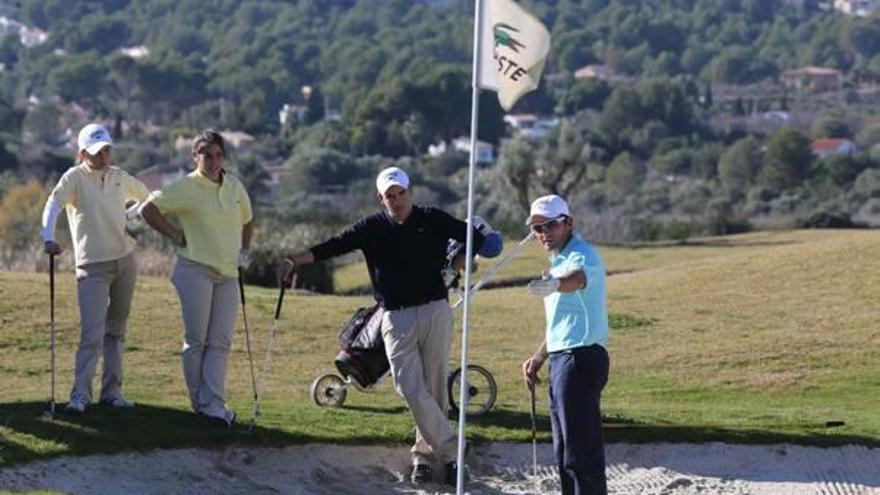 Un grupo de jugadores de golf charlan al lado de un hoyo.