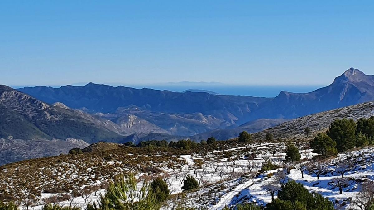 La ladera de Aitana, nevada. Al fondo, la Serra de Bèrnia y la isla de Eivissa