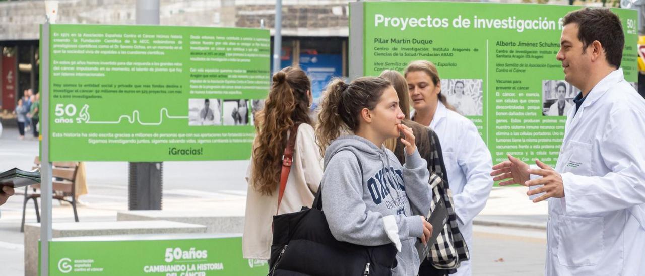 Alberto Jiménez Schuhmacher explica su proyecto a una joven y, al fondo, Pilar Martín Duque. | AECC ARAGÓN