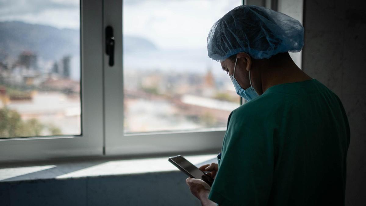 Un sanitario mira su teléfono móvil en un descanso de quirófano.