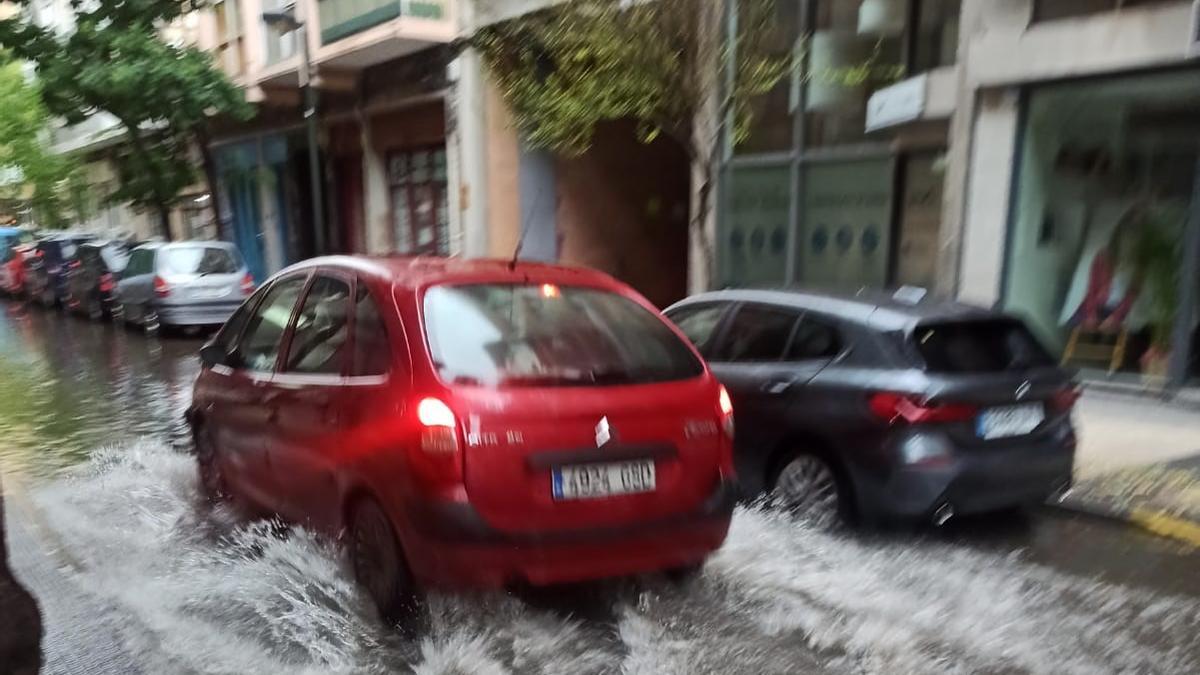 Un coche avanza dejando una estela de agua por la calle del Doctor Horno, en Zaragoza.