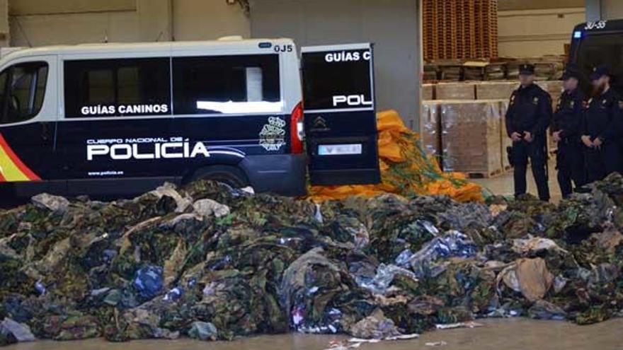 Agentes de la Policía Nacional custodian la montaña de ropa de camuflaje.