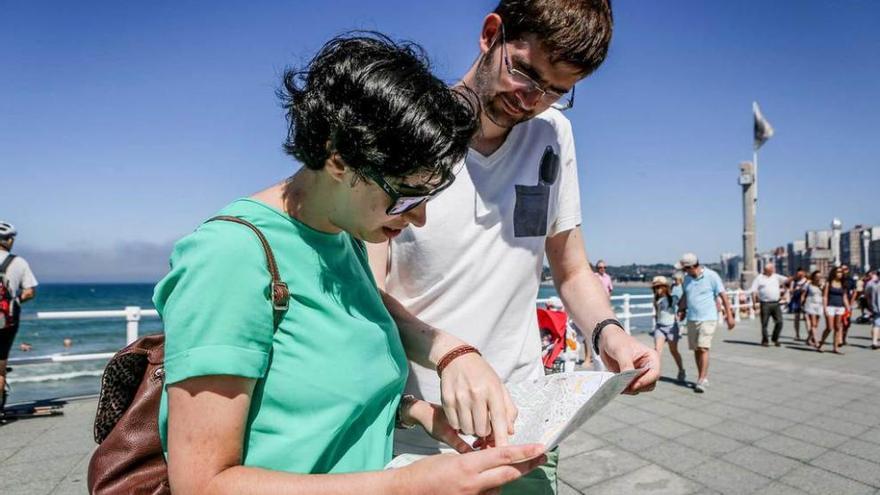 Dos turistas consultan un plano en el paseo del Muro.