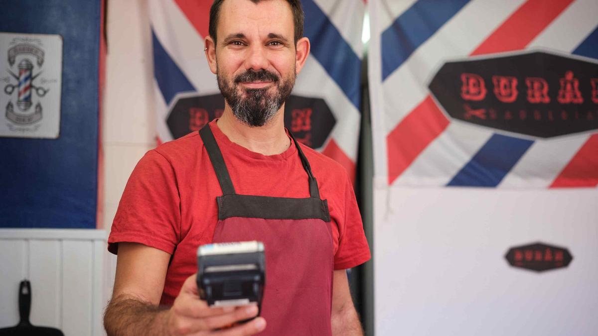 Javier Durán, propietario de la peluquería Durán, con un datáfono