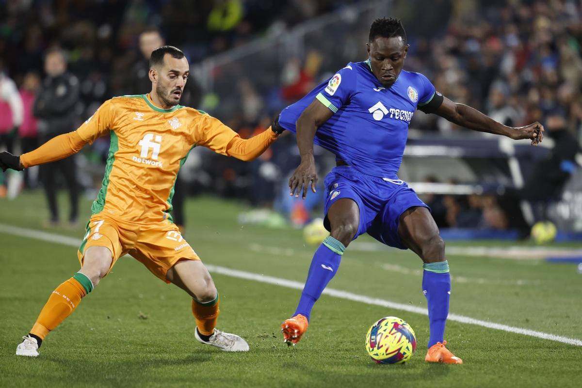 El defensa del Getafe Djené Dakonam (d) lucha con Juanmi, del Betis, durante el encuentro correspondiente a la jornada 19 de Primera División en el Coliseum Alfonso Pérez, en Getafe. EFE / Chema Moya.