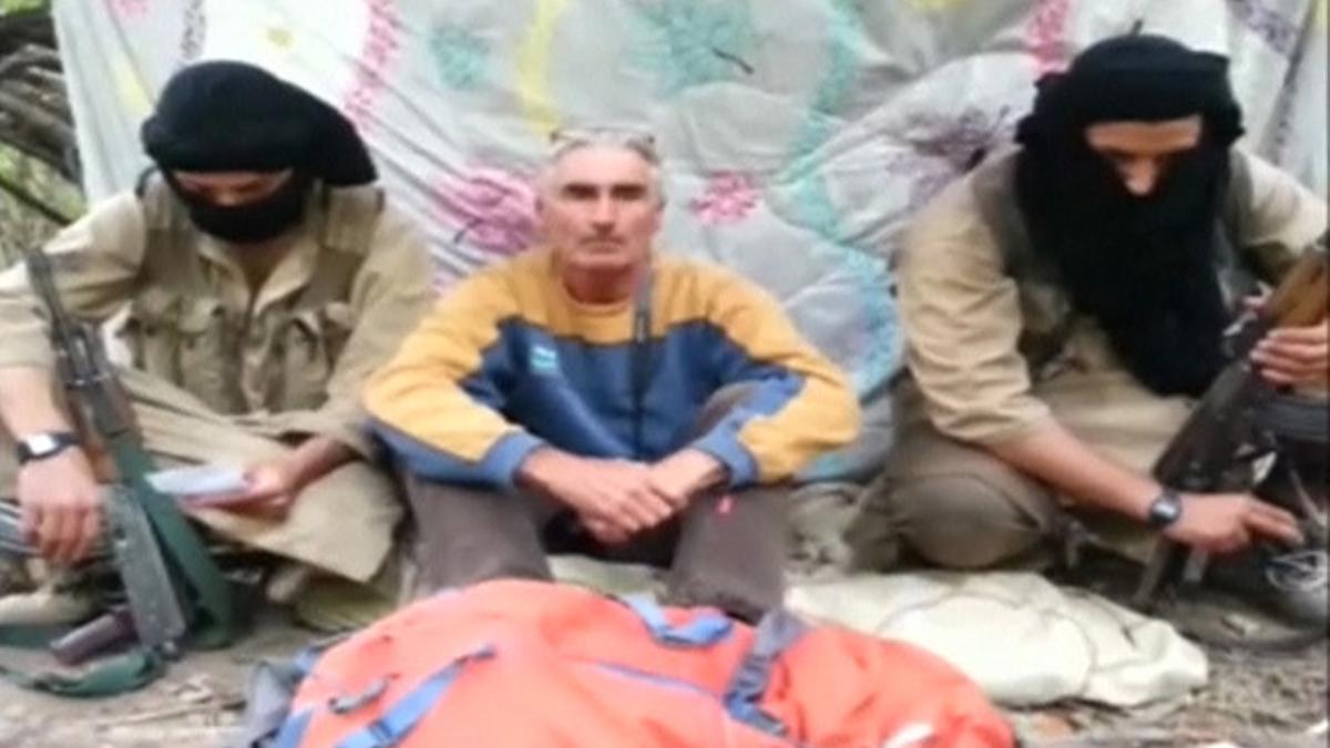 El turista francés, que se autoidentifica como Hervé Gourdel, sentado en medio de sus secuestradores, en una imagen de vídeo.