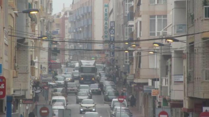 Imagen de una calle de Torrevieja con alumbrado encendido a plena luz del día.