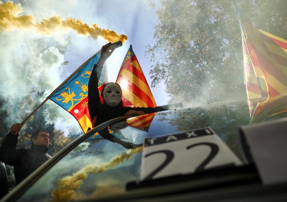 A masked protestor holds a smoke bomb during a ...