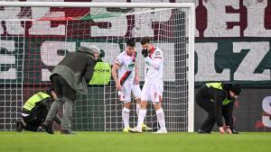 Los jugadores del Ausburgo y miembros de seguridad despejando el césped