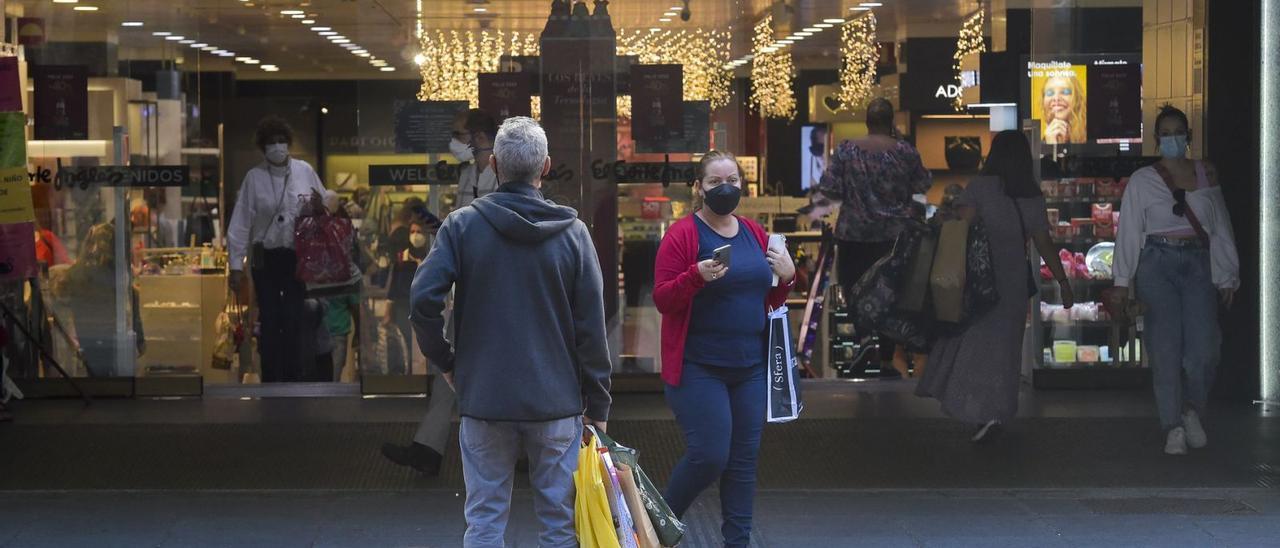 Varios usuarios entran y salen con sus compras de un comercio en la capital grancanaria. | | ANDRÉS CRUZ