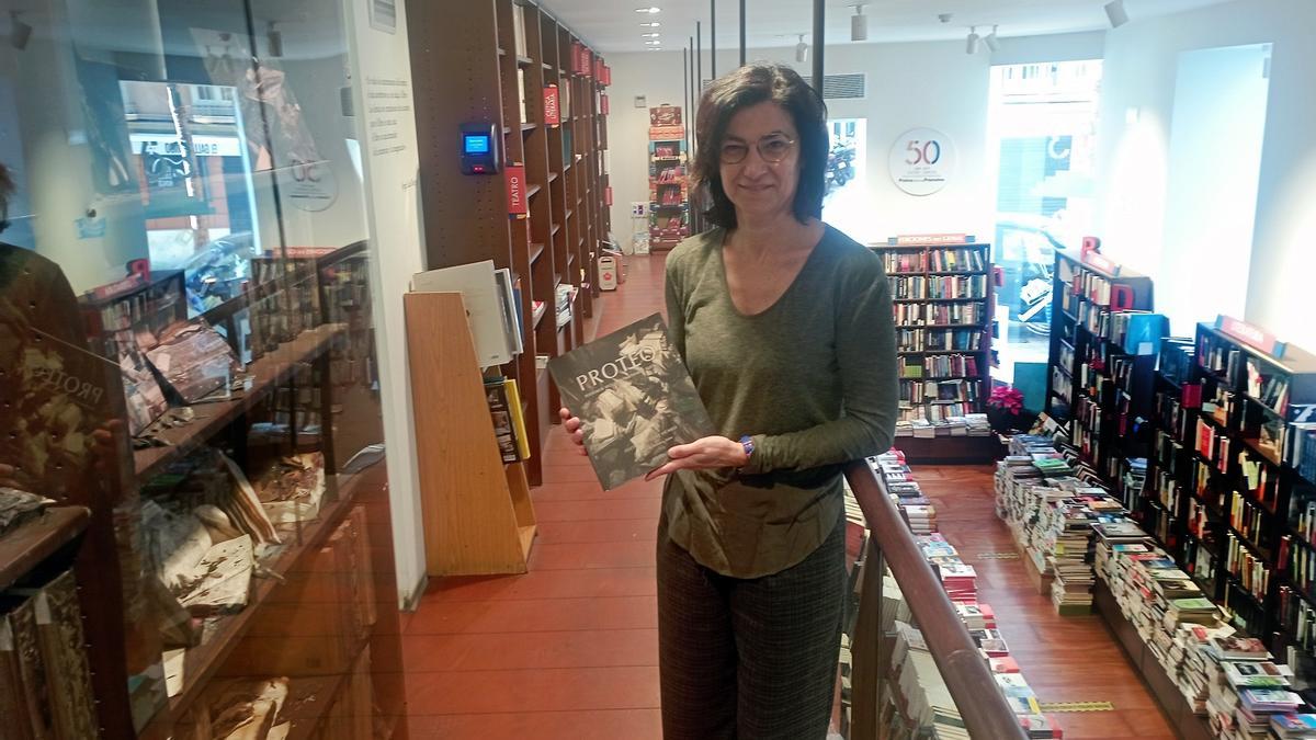 Lucía Rodríguez Vicario, esta semana en Proteo con su libro de fotos a beneficio de la librería, junto a baldas con libros quemados en 2021.
