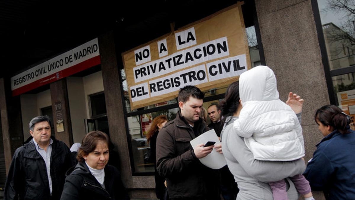 El exterior de un registro civil en Madrid, el pasado lunes, con un cartel que muestra las críticas a la privatización de este servicio público.