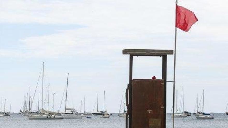 Algunas personas tumbadas en la arena, ayer por la mañana, frente a la torre de vigilancia de Talamanca con la bandera roja.